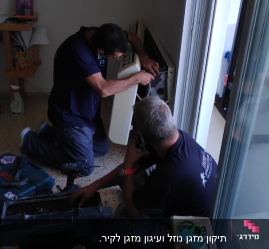 שני אנשים מתקנים מזגן עם כלים על הרצפה